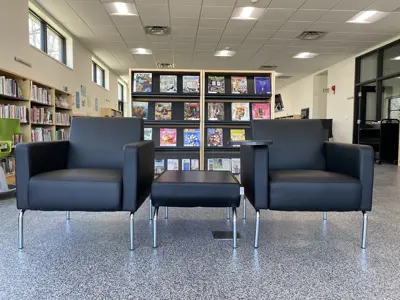 two chairs facing the camera, situated in front of the magazine racks